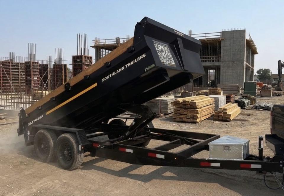 Front three-quarter view of the 7x14 dump trailer with battery box and roller tarp